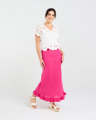 Woman wearing a white lace top and pink skirt on a white background
