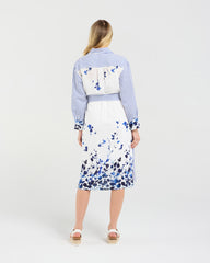 Woman wearing a blue and white striped shirt with a floral skirt on a white background
