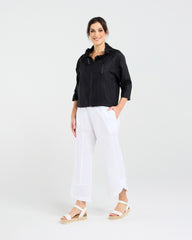Woman wearing a black jacket and white pants on a white background
