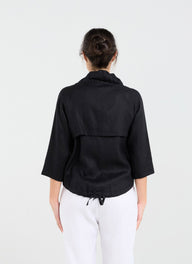 Person wearing a black jacket and white pants on a white background
