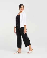 Woman wearing a white jacket and black pants on a white background
