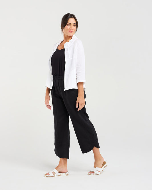 Woman wearing a white jacket and black pants on a white background