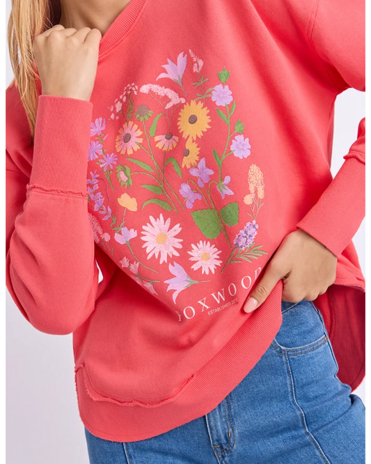 Red sweatshirt with floral design and 'FOXWOOD' branding worn by a person.
