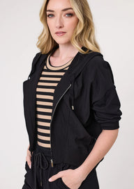 Woman wearing a black jacket over a striped shirt on a white background