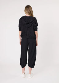 Person wearing a black hoodie and black pants on a white background