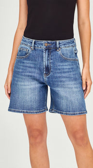 A person wearing medium-wash blue denim shorts with a black sleeveless top, shown from the chest to the upper thighs against a plain light background.