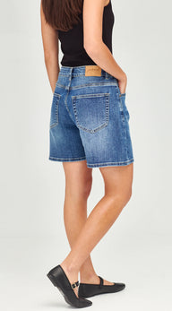 A model from the back wearing blue denim shorts, a black tank top, and black flat shoes, standing against a light gray studio background.