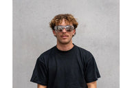 Person wearing safety goggles against a gray background