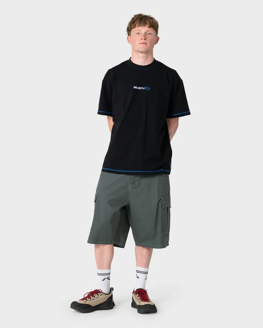 Person wearing a black t-shirt with a logo and green shorts on a white background