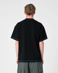 Person wearing a black polo shirt with blue trim on a white background