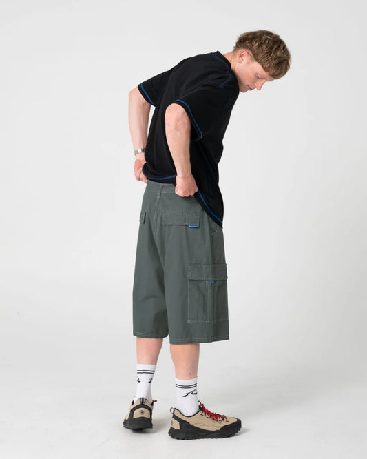 Person wearing a black t-shirt and green cargo shorts on a white background