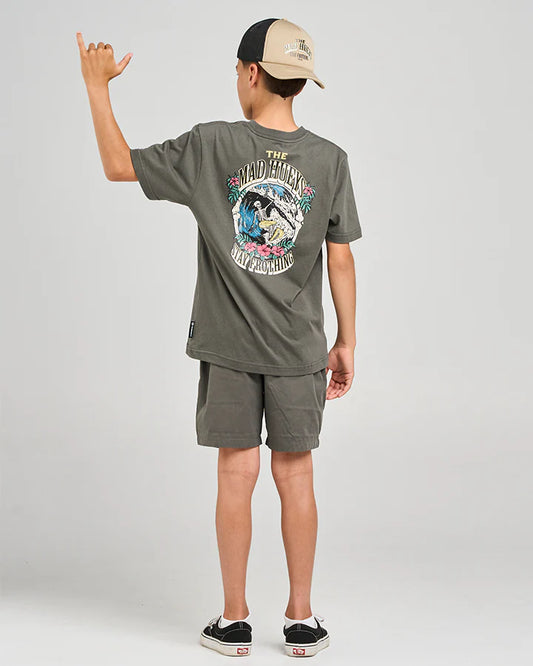 Child wearing a graphic t-shirt and shorts with a cap, standing against a plain background
