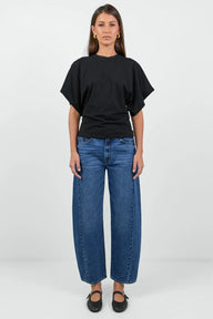 Woman wearing a black oversized t-shirt and blue jeans on a white background