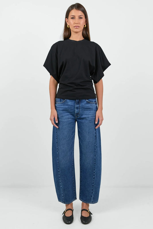 Woman wearing a black oversized t-shirt and blue jeans on a white background
