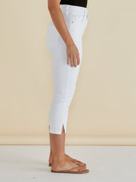 White jeans with a front slit worn by a person on a beige background