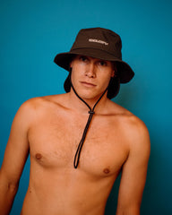 Man wearing a black bucket hat against a blue background