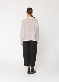 Person wearing a light pink sweater and black pants on a white background
