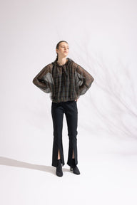 Person wearing a plaid shirt and black pants on a white background