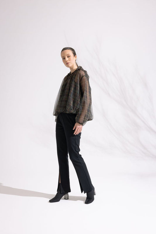 Person wearing a sheer black top and black pants on a white background