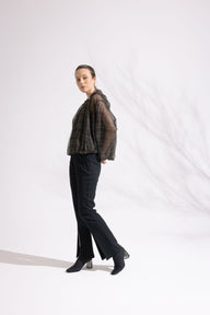 Person wearing a plaid shirt and black pants on a white background