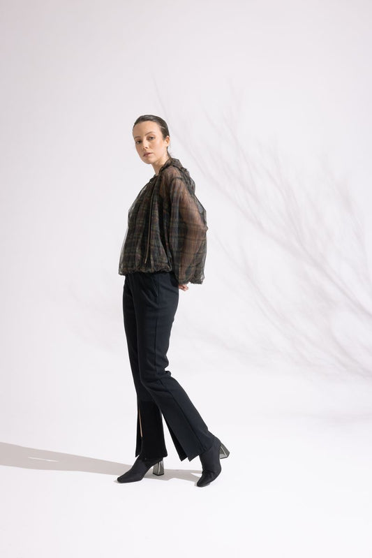 Person wearing a plaid shirt and black pants on a white background
