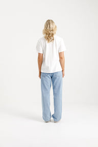 Woman wearing Home-Lee Chris Tee in white with a Blossom Berry bow design & blue jeans on a white background