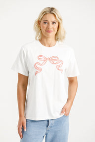 Woman wearing Home-Lee Chris Tee in white with a Blossom Berry bow design on a white background