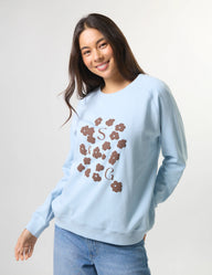 Woman wearing a light blue sweatshirt with floral designs and text on a plain background