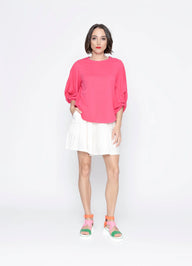 Woman wearing a pink blouse and white skirt on a white background