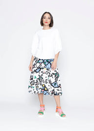 Woman wearing a white top and colorful patterned skirt on a white background