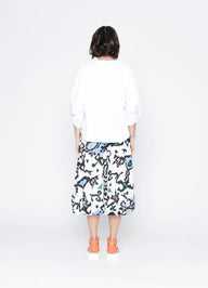 Person wearing a white shirt and colorful skirt on a white background