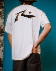 Person wearing a white t-shirt with a logo on the back against a blue wall.