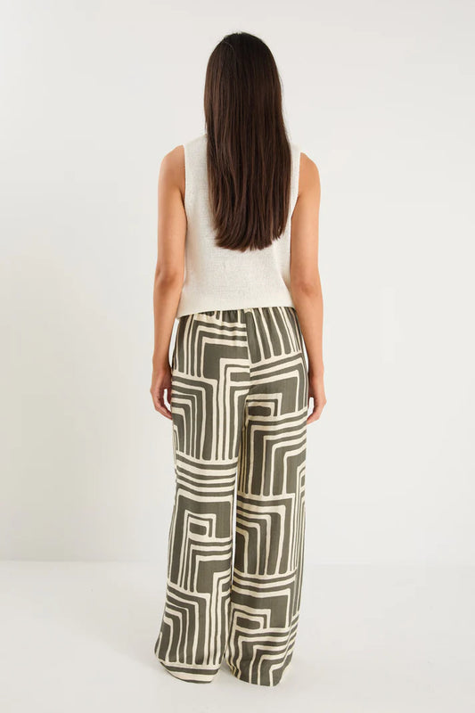 Woman wearing a sleeveless top and patterned pants on a white background