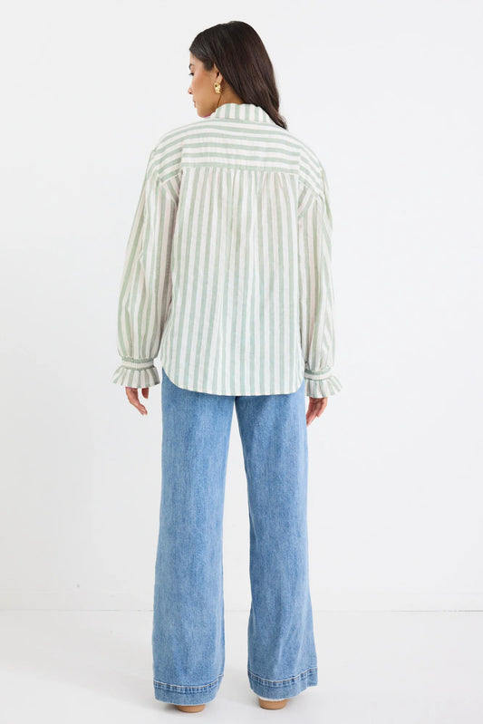 Person wearing a striped shirt and blue jeans on a white background
