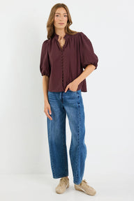 Woman wearing a chocolate blouse and blue jeans on a white background