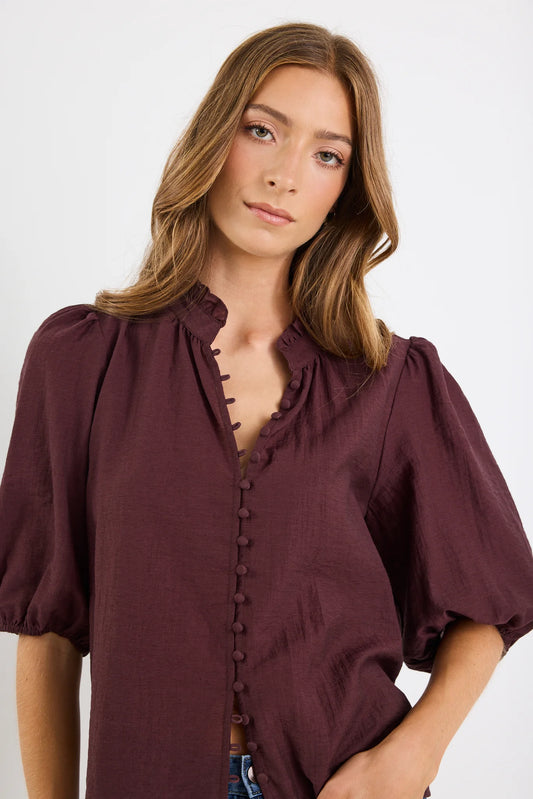 Woman wearing a chocolate blouse with puffed sleeves on a white background