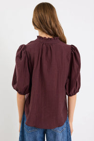 Person wearing a chocolate blouse with puffed sleeves on a white background