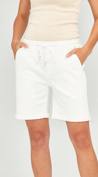 White women's shorts with a drawstring waist and side pockets, shown on a model wearing a beige top against a light gray studio background.