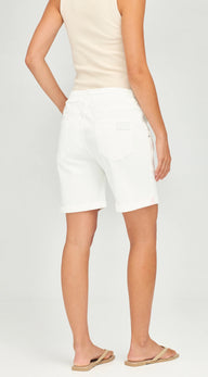 A model shown from the back wearing white denim shorts, a light beige tank top, and tan flip-flops against a light gray studio background.