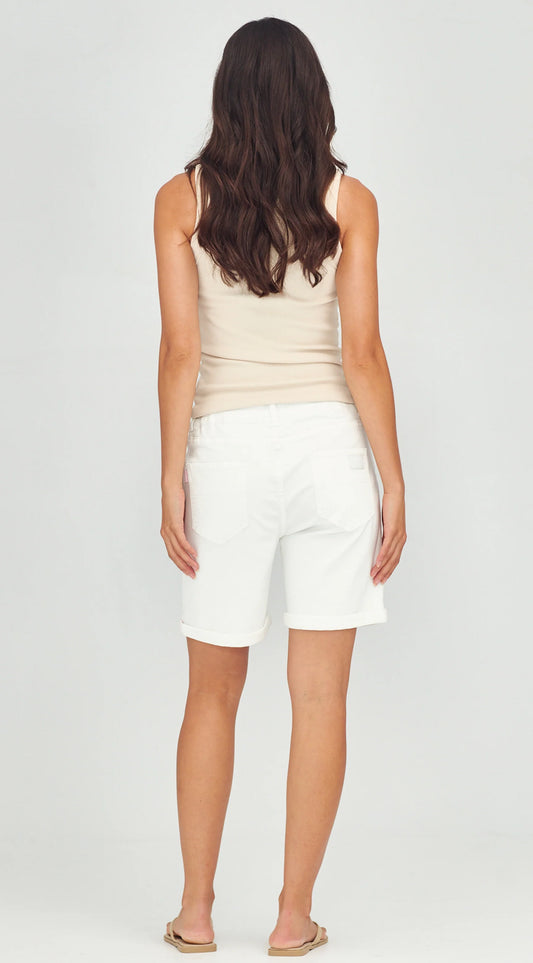 A woman shown from the back wearing a light beige tank top and white shorts against a plain light gray studio background.