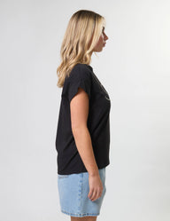 Woman wearing a black t-shirt and denim shorts on a white background