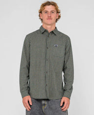 Man wearing a green checkered shirt with a brand logo on a gray background