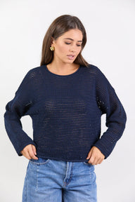 Woman wearing a navy blue knitted sweater and blue jeans on a white background