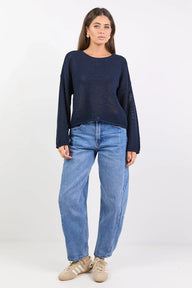 Woman wearing a navy sweater and blue jeans on a white background