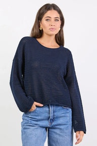 Woman wearing a navy blue knitted sweater and blue jeans on a white background