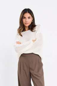 Woman wearing a white sweater and brown pants on a white background