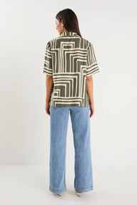 Woman wearing a patterned shirt and blue jeans on a white background