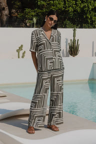 Woman in a geometric patterned outfit standing by a pool with cacti in the background