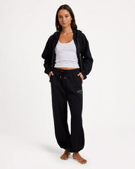 Woman wearing a black tracksuit with a white top on a white background