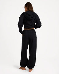 Person wearing a black hoodie and black pants on a white background